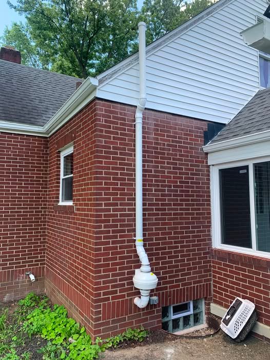 Radon mitigation system pipe on a brick home exterior in West Des Moines, IA