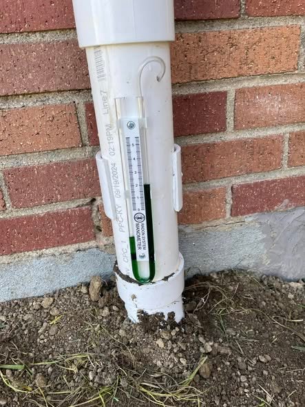 Manometer gauge confirming a radon mitigation system is running